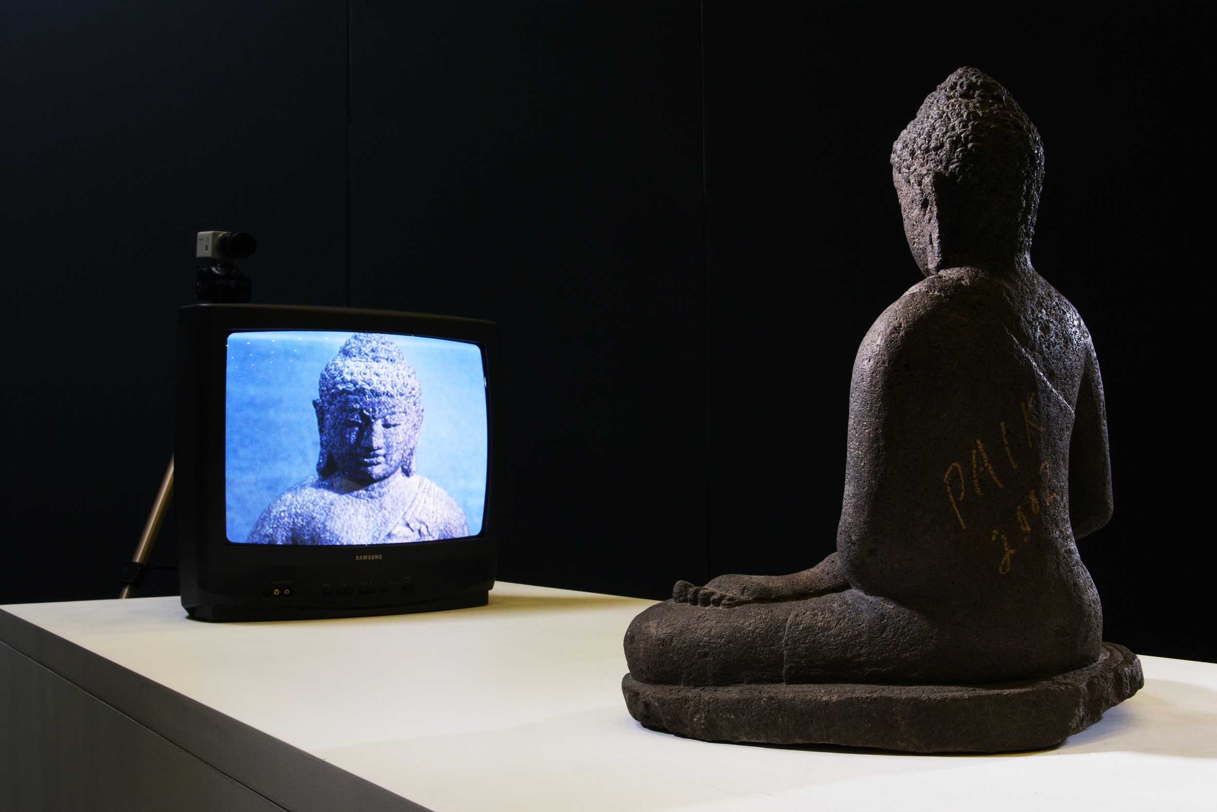 Buddha statue sitting in front of closed circuit television
